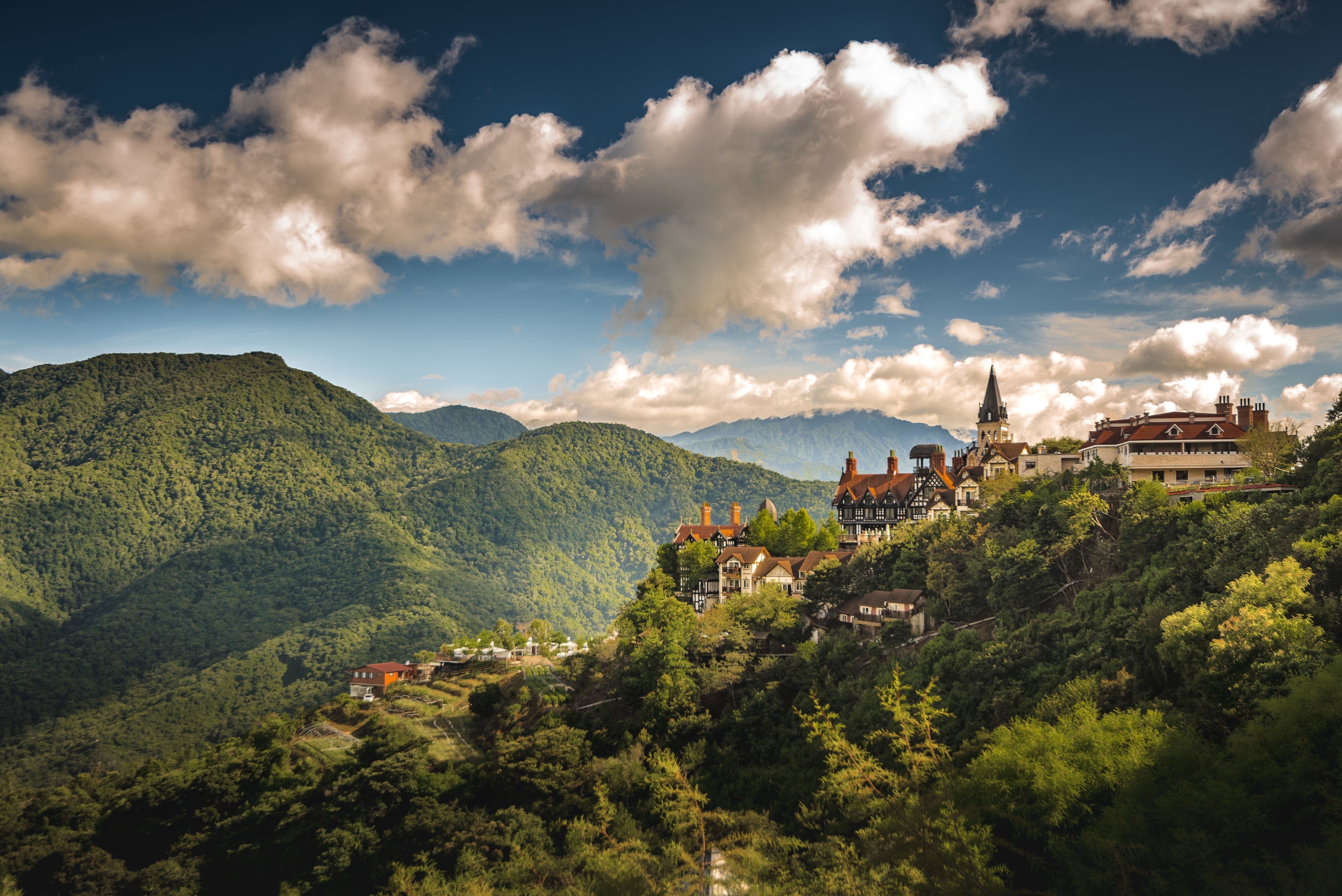 aerial-shot-small-village-hill-surrounded-by-forested-mountains.jpg